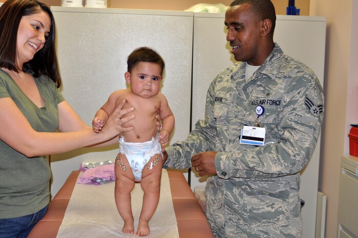 Amanda Polk, wife of Senior Airman Jeremiah Polk, 99th Security Forces confinement specialist, comforts their daughter Miah after she received vaccinations from Senior Airman Zeraiacob Kidune, 99th Medical Group immunizations technician April 5, 2012 at Nellis Air Force Base, Nev. The 99th Medical Group's pediatric clinic now offers immunizations within the clinic. (U.S. Air Force photo by Staff Sgt. William P.Coleman)  