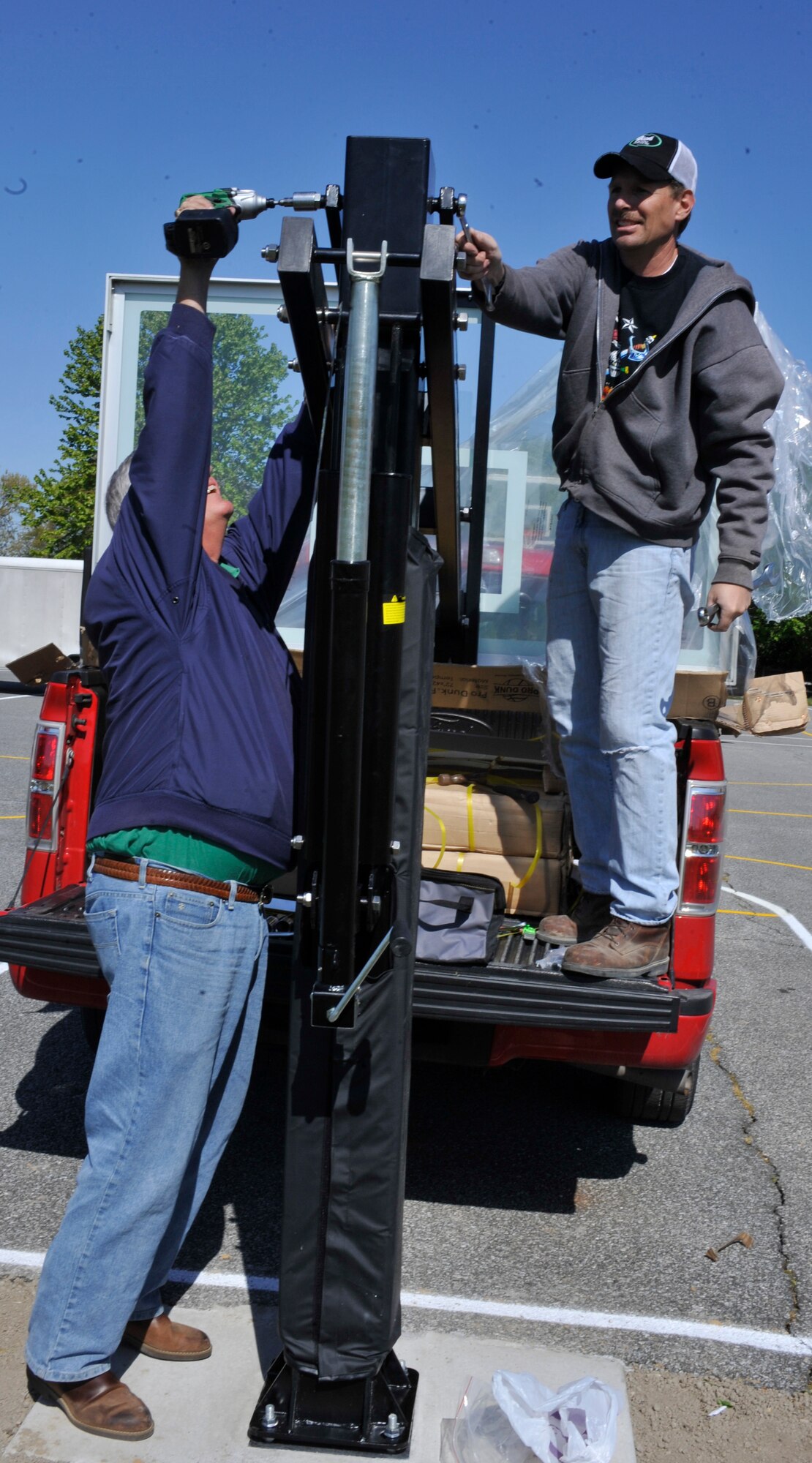 Mark Newell, left, a contractor with CH2M Hill, and Rick Stoops, a contractor with George & Lynch, install the adjustable arm of a new basketball hoop April 13, 2012, at Welch Elementary School at Dover Air Force Base, Del. The team of three contractors donated the hoops to the school to give back to the military community. (U.S. Air Force photo by Tech. Sgt. Chuck Walker)
