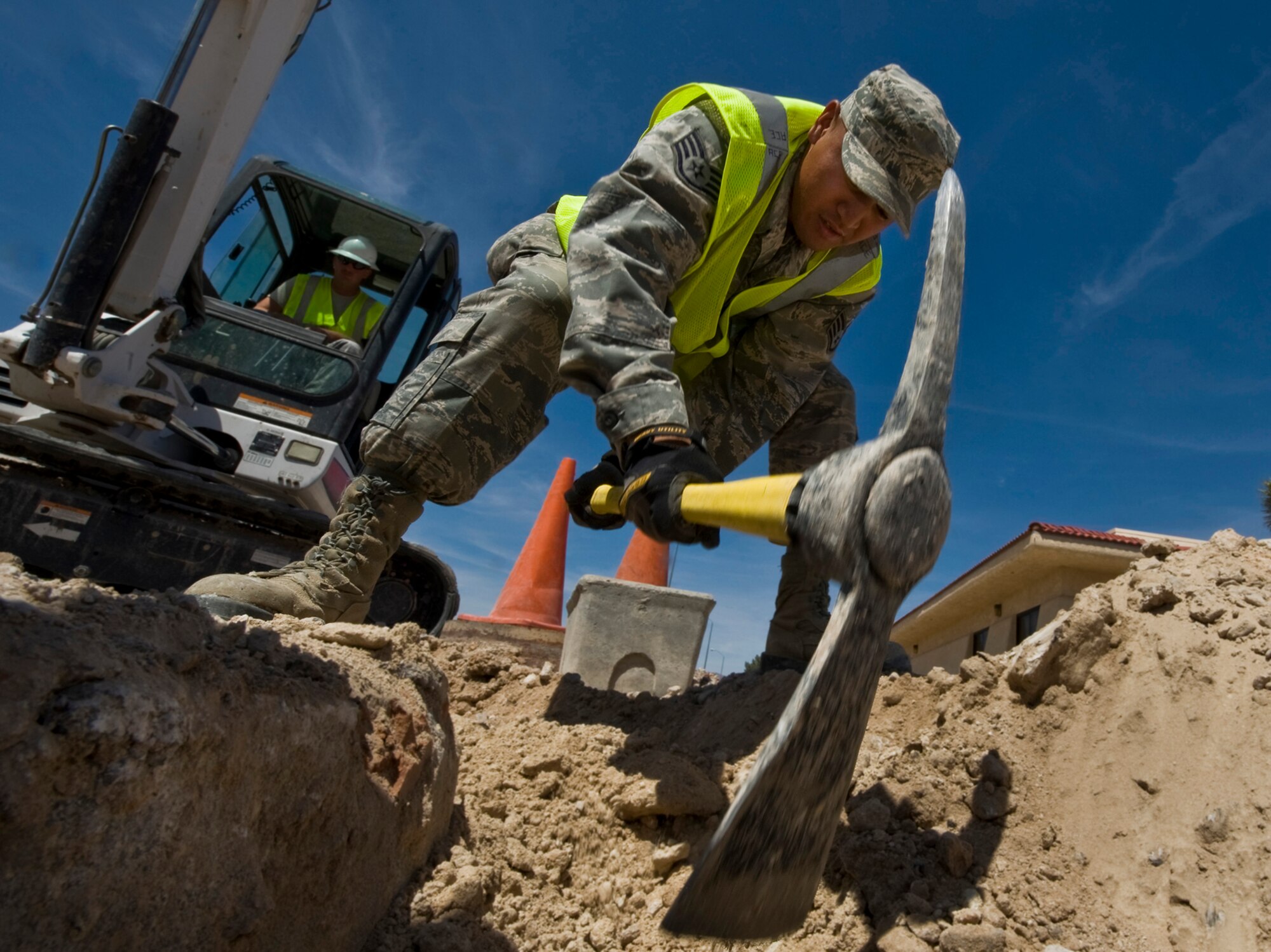 U.S. Air Force Staff. Sgt. Aaron Cumming, 99th Civil Engineer Squadron pavement and equipment operator craftsman, excavates a manhole cover during the construction of a roundabout April 14, 2012, at Nellis Air Force Base, Nev. The intent of the roundabout is to alleviate traffic congestion in between the gates.  (U.S. Air Force photo by Airman 1st Class Daniel Hughes)
