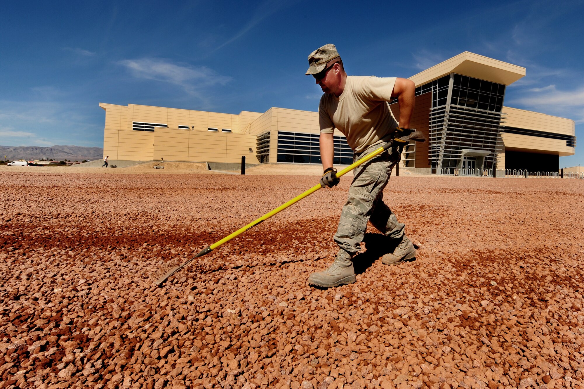 U.S. Air Force Staff Sgt. Chris Wright, 99 Civil Engineer Squadron pavement and construction journeyman, spreads gravel for a xeriscape design at the new Warrior Fitness Center at Nellis Air Force Base, Mar. 20, 2012.  Xeriscaping is conserving water by landscaping in ways that reduce or eliminate the need to use water for irrigation. (U.S. Air Force photo by Staff Sgt. William P.Coleman)
  

