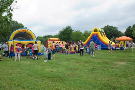 Children line up to jump on three of the oversized inflatable moon bounces April 14 as part of Famaganza at Joint Base San Antonio-Randolph, Texas.  Famaganza is a yearly family celebration that includes performances, games, prizes and a book fair. (U.S. Air Force photo by Benjamin Faske)