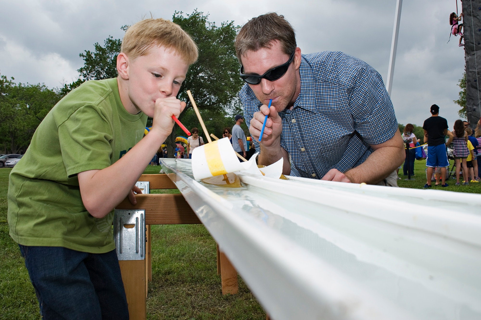 Ray Quenneville, 902nd Comptroller Squadron, and his son, Kyle, use straws to blow their boats across the finish line April 14 at Joint Base San Antonio-Randolph, Texas. Famaganza is a yearly family celebration that includes performances, games, prizes and a book fair. (U.S. Air Force photo by Benjamin Faske)