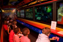 Children test their gaming skills against one another at the  "Games 2 U" trailer April 14 as part of Famaganza at Joint Base San Antonio-Randolph, Texas. Famaganza is a yearly family celebration that includes performances, games, prizes and a book fair. (U.S. Air Force photo by Benjamin Faske)
