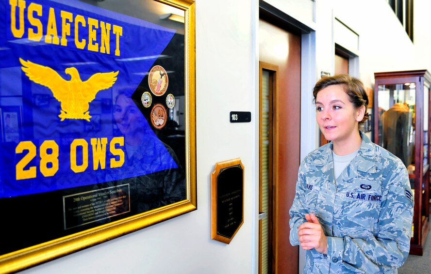 Senior Airman Rachel Davis, 28th Operational Weather Squadron forecaster, gives a brief history of the squadron by a guide-on flag and some squadron memorabilia in the 28th OWS lobby, Shaw Air Force Base, S.C., April 6, 2012. Volunteers from the 28th OWS created an Air Force memorabilia display in their lobby to help squadron members and visitors gain a sense of pride in their heritage. (U.S. Air Force photo by Senior Airman Daniel Phelps/Released)