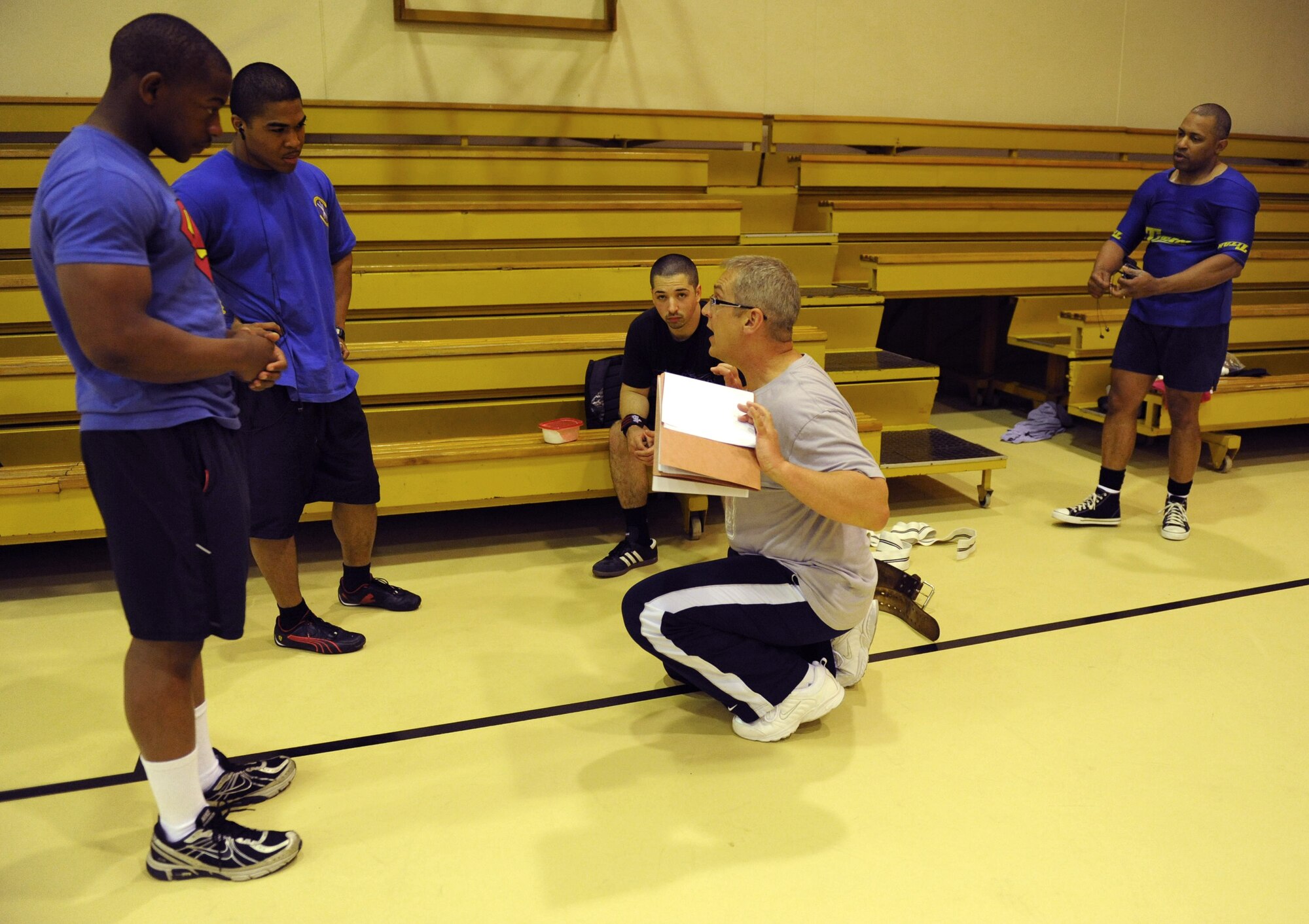 Ernie Fasoldt, 39th Force Support Squadron fitness and sports director, kneeling, gives a safety brief to, from right to left, Jimmy Scott, Adam Plummer, Julian Clarke, and William Jones, during a powerlifting competition April 14, 2012, at Incirlik Air Base, Turkey. Fasoldt coordinated the competition with the help of the fitness center staff. (U.S. Air Force photo by Senior Airman Anthony Sanchelli/Released)
