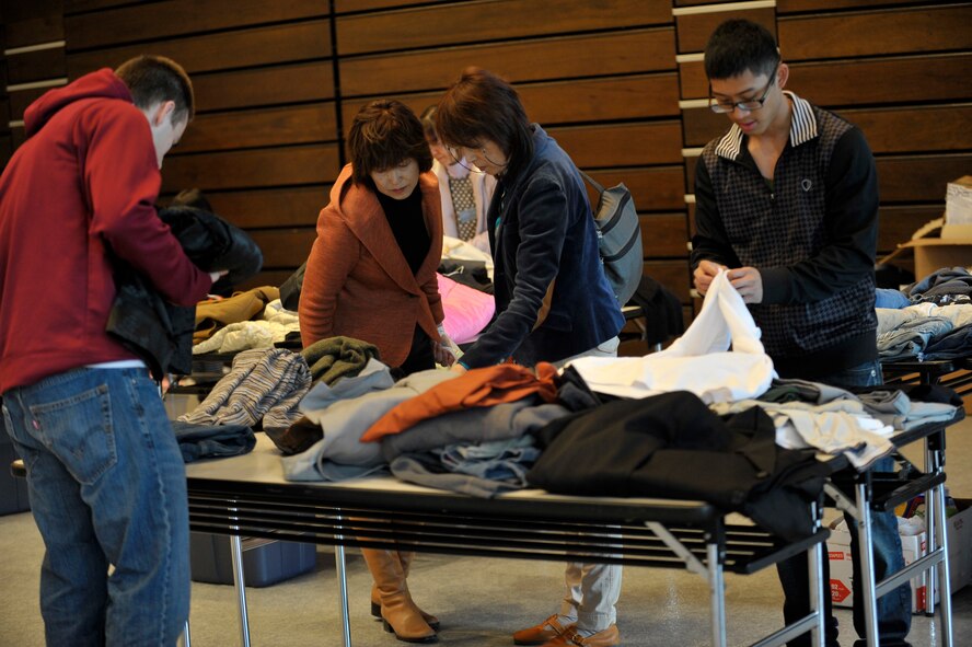 Members of the Misawa Air Base community fold donated clothes as people displaced from last year's earthquake and tsunami look through them during a Mini-American Day event at Hanamaki, Japan, April 14, 2012. More than 200 people attended the event. The Mini-American Day was put on for the people displaced from their homes in the Iwate Prefecture, Japan, by the earthquake and subsequent tsunami of March 11, 2011. (U.S. Air Force photo by Staff Sgt. Nathan Lipscomb/Released)