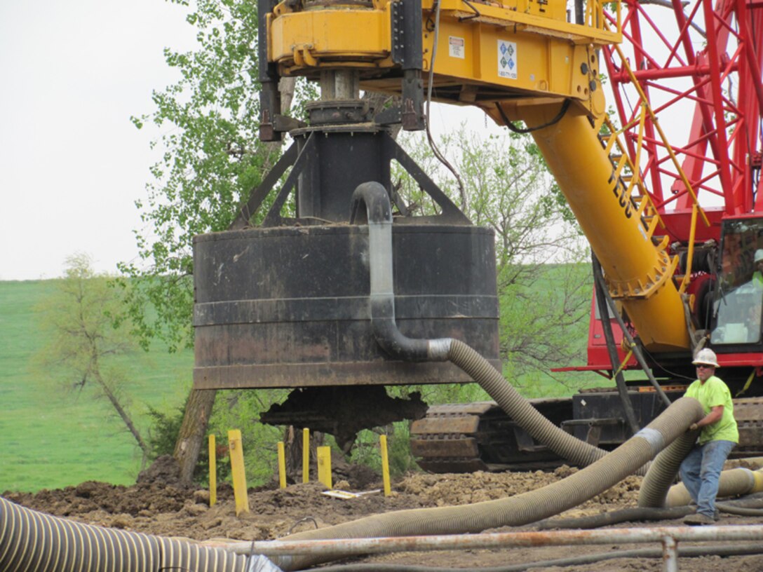 A contract employee repositions the vapor collection line during source area treatment operations at the former Offut Air Force Base. The bit of the large diameter auger is visible below the off-gas collection hood, in the center of the photo. 