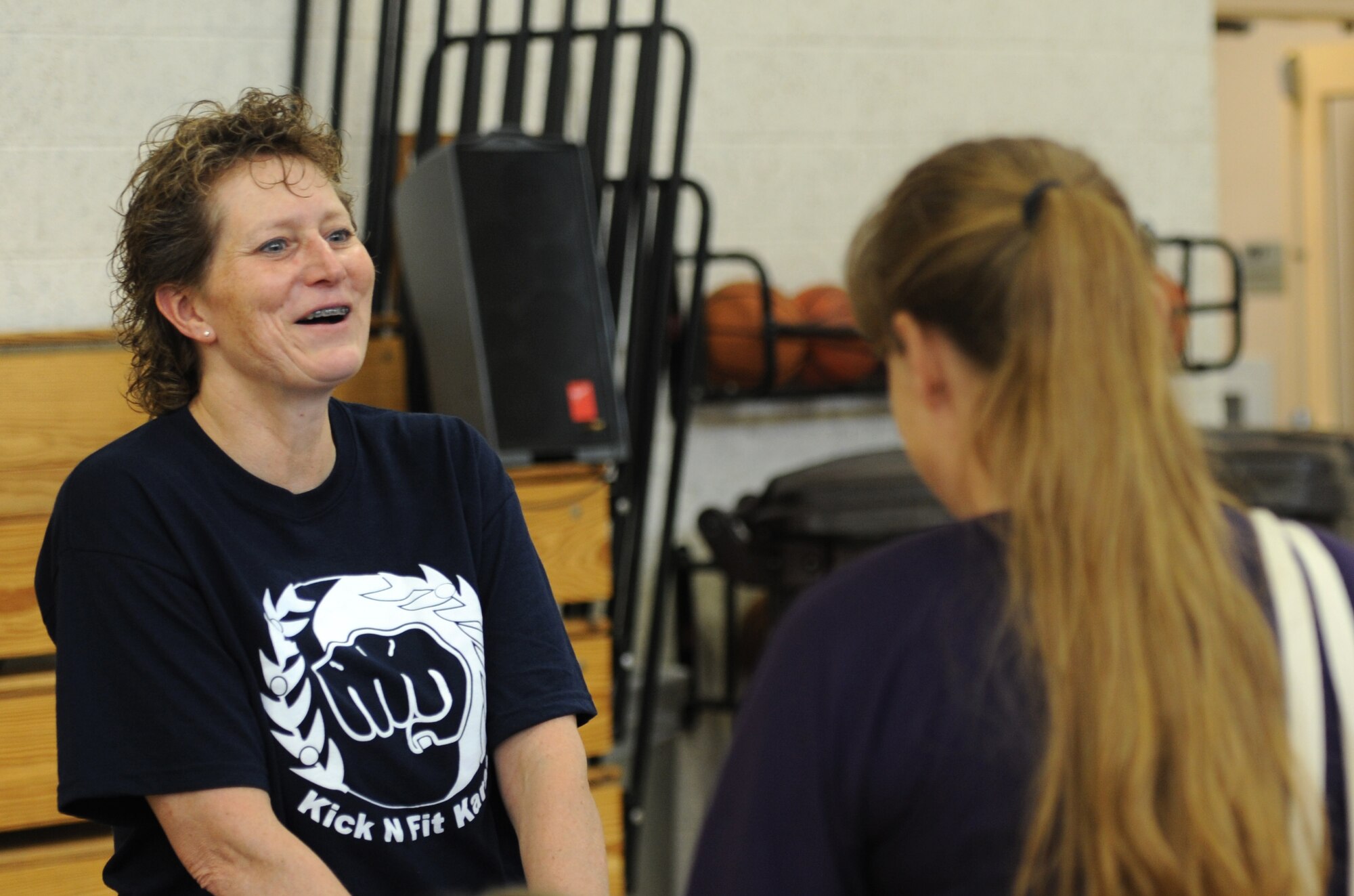 Regina Anguiano, left, the senior instructor at Kick N Fit Karate in Enid, talks about the training she offers with a Team Vance member at the Health and Wellness Fair held April 13 in the Youth Center’s gymnasium at Vance Air Force Base, Okla. (U.S. Air Force photo/ Airman 1st Class Frank Casciotta)