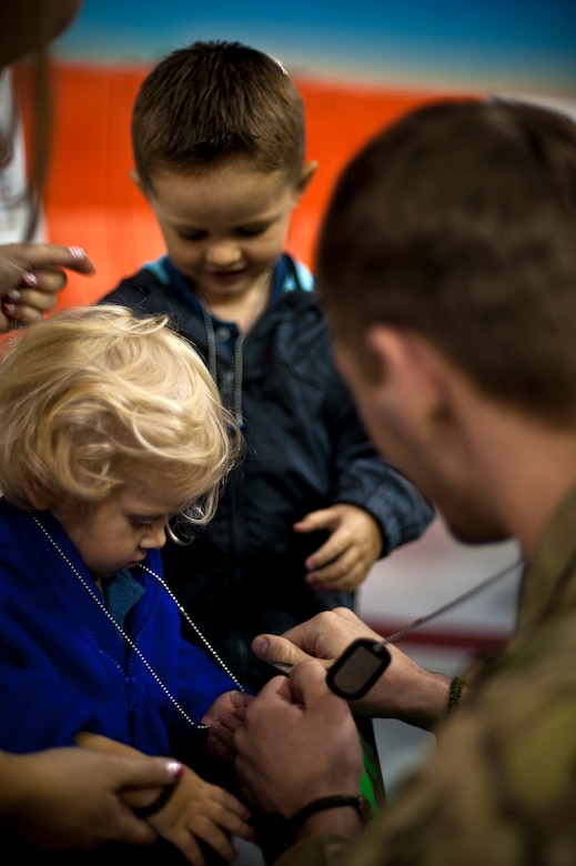 U.S. Air Force Staff Sgt. Casey Strauss, a special operations forces fly away security team from 1st Special Operations Security Forces Squadron, hands dog tags to his two children Caden (left), and Carter (middle) at the 16th Aircraft Maintenance Unit hangar on Hurlburt Field, Fla., April 6, 2012. Members deployed overseas for multiple months in support of overseas contingency operations. (U.S. Air Force photo/Airman 1st Class Christopher Williams)(Released)