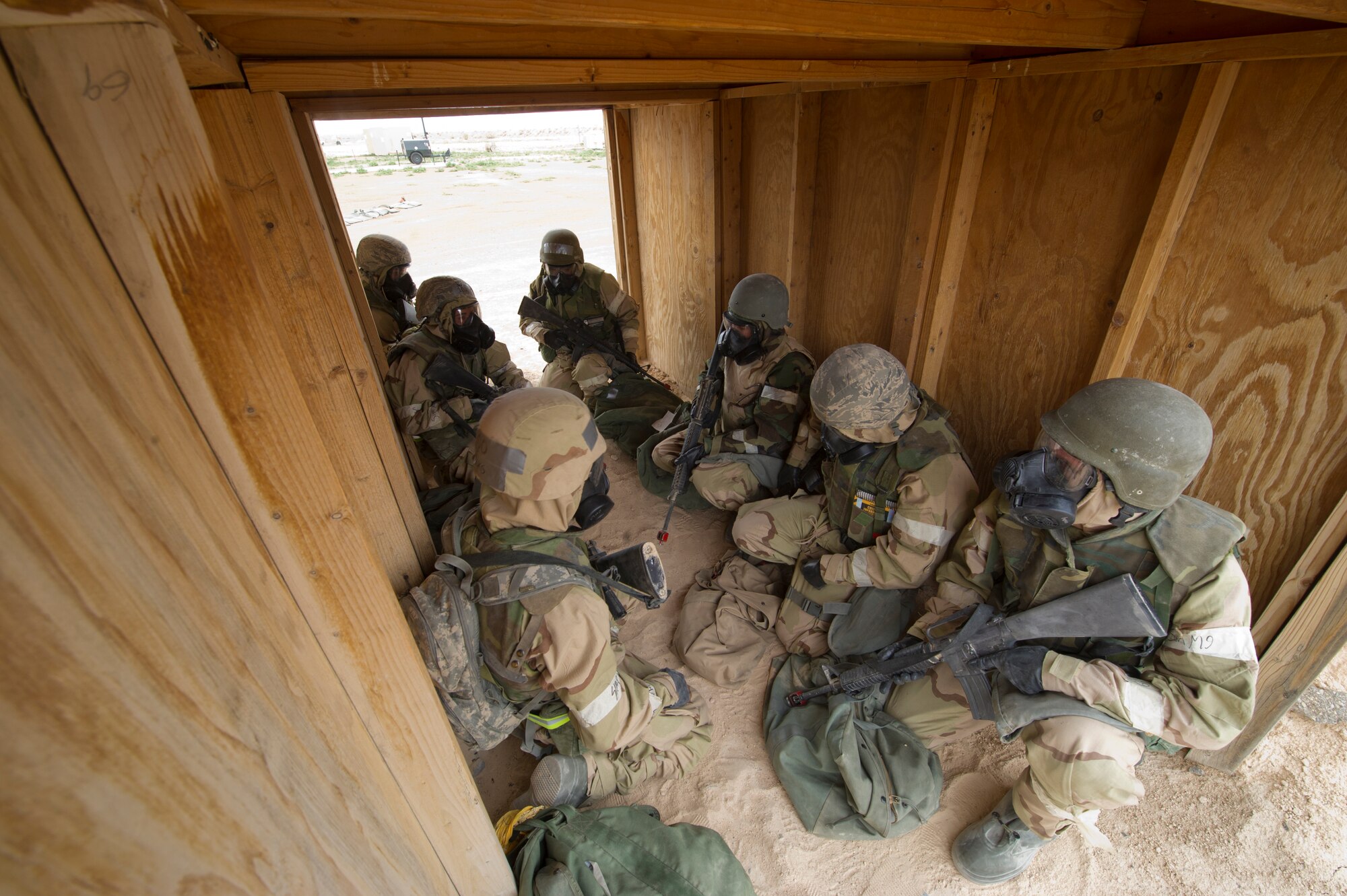 HOLLOMAN AIR FORCE BASE, N.M. – Airmen from the 49th Civil Engineer and Materiel Maintenance Squadrons take cover under a hardened shelter in level four mission-oriented protective postures during a Bivouac exercise April 11. During a simulated base attack, Airmen sought immediate shelter in a solid structure as a preventative measure, as well as donned chemical protection gear to protect themselves from any possible form of bio-warfare used by hostile forces. (U.S. Photo by Airman 1st Class Michael Shoemaker/Released)