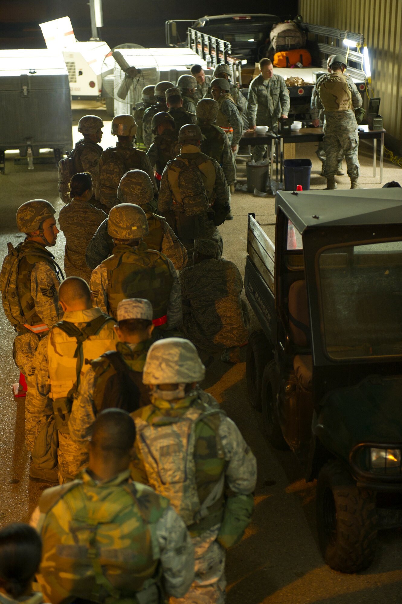 HOLLOMAN AIR FORCE BASE, N.M. – Airmen from the 49th Civil Engineer and Materiel Maintenance Squadrons line up for weapon issue during a Bivouac exercise April 10. The Airmen donned full protective measures, including a Kevlar vest, helmet, and M-16 assault rifle, and assumed roles at defensive fighting positions and entry control points around the perimeter of a deployment training site, during the four-day exercise. (U.S. Photo by Airman 1st Class Michael Shoemaker/Released)
