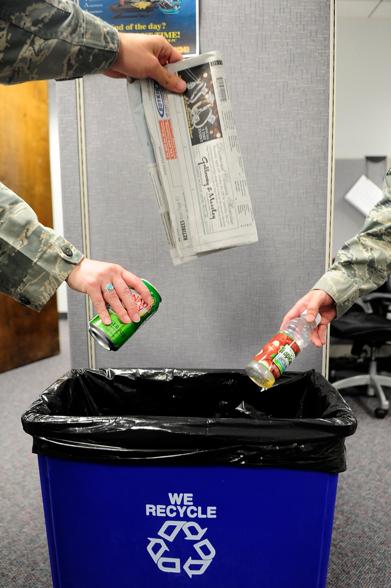 U.S. Air Force Airmen toss a can, a newspaper and a bottle into a recycling bin at Shaw Air Force Base, S.C., April 18, 2012. The Air Force encourages recycling to help preserve the environment. (U.S. Air Force photo by Airman 1st Class Hunter Brady/Released)