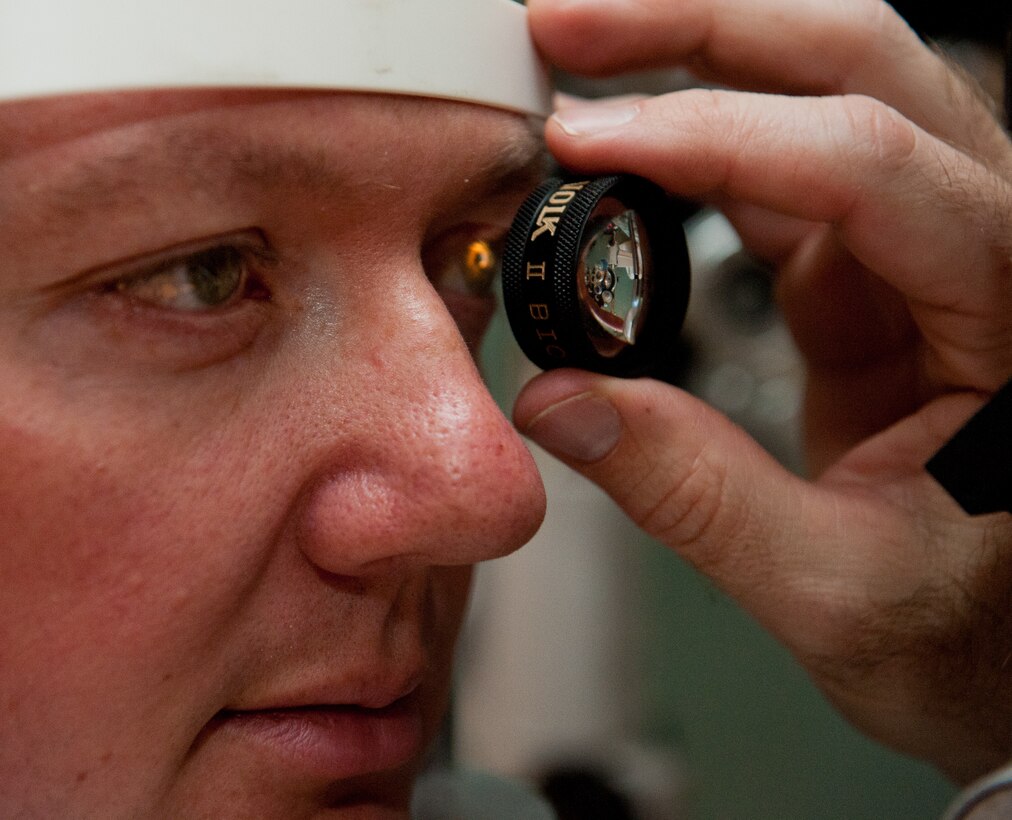 Maj. Bryan Kemper, 28th Medical Operations Squadron optometrist, performs a slit lamp test under magnification on U.S Army Staff Sgt. David Neugebauer, 235th Military Police Company training NCO, during a routine eye exam in the optometry clinic at Ellsworth Air Force Base, S.D., April 12, 2012. By using magnification, Kemper was able to evaluate the retna and back of the eye to ensure the entire eye was healthy. (U.S. Air Force photo by Airman 1st Class Kate Thornton/Released)