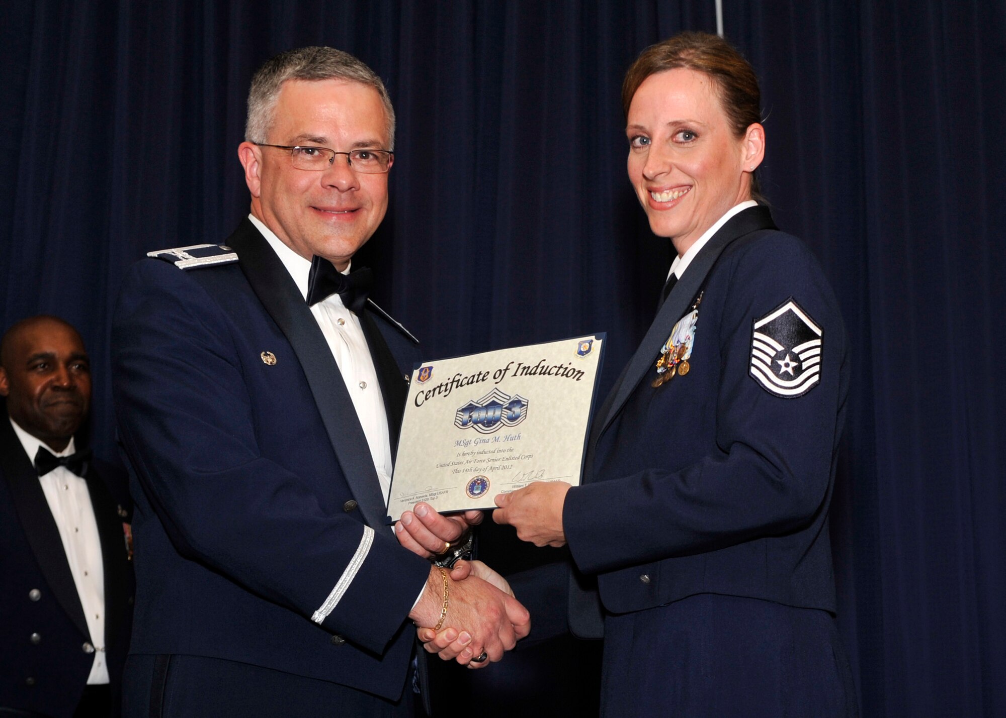Master Sgt. Gina Huth, 512th Airlift Wing, receives a certificate of induction from Col. Randal L. Bright, 512th AW commander, during the wing's 7th Annual Senior NCO Induction Ceremony April 14, 2012, at the Landings, Dover Air Force Base, Del. She was one of 21 new master sergeants inducted into the Senior NCO Corps. (U.S. Air Force photo/Tech. Sgt. Charles Walker)