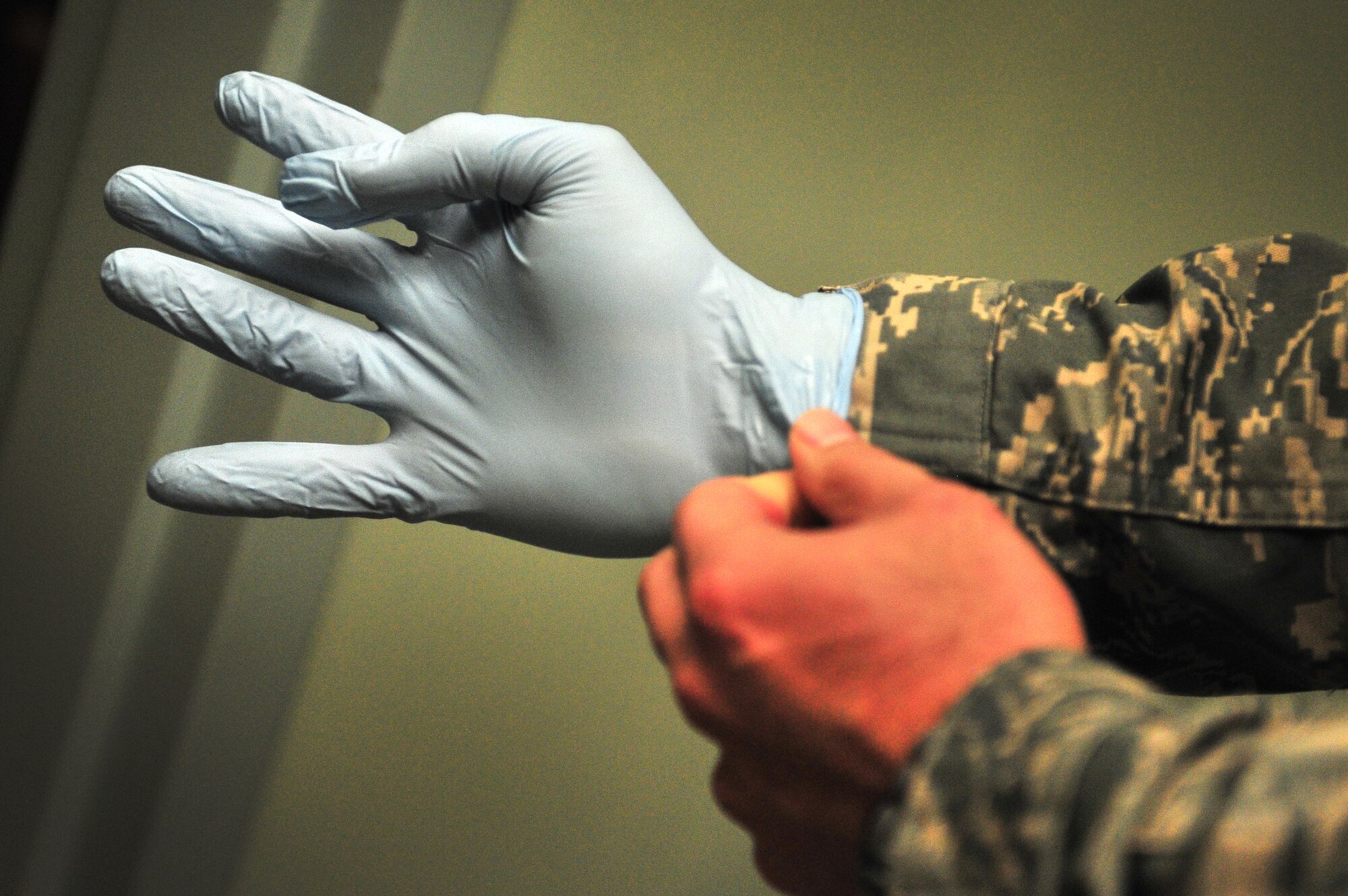 A first responder dons rubber gloves during a tornado natural disaster exercise at Cannon Air Force Base, N.M., April 5, 2012. Training exercises provide a safe and controlled environment to practice tactics, techniques and procedures. (U.S. Air Force photo by Tech. Sgt. Josef Cole)