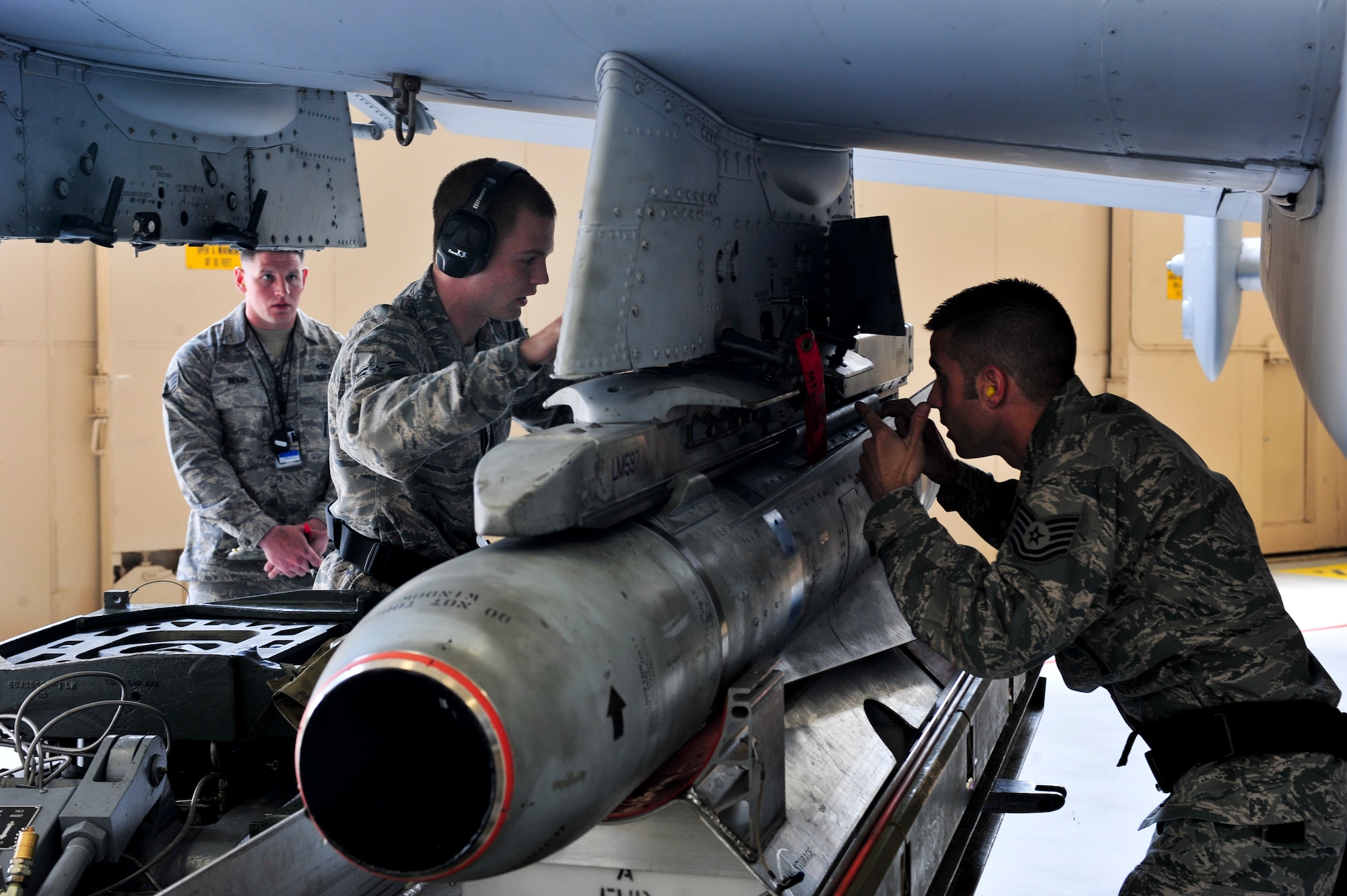 U.S. Air Force Tech. Sgt. Joshua Fiasco, right, and Airman 1st Class Trenton Metyk, 23d Aircraft Maintenance Squadron, 75th Aircraft Maintenance Unit weapons load crew members, secure a bomb onto an A-10C Thunderbolt II during a quarterly weapons load crew competition at Moody Air Force Base, Ga., April 13, 2012. Airmen from the 74th and 75th AMUs competed to load various munitions onto an A-10 the fastest and safest. Before the load-off began, the load crews underwent a 25-question job knowledge test, toolbox inspection and uniform inspection. (U.S. Air Force photo by Staff Sgt. Stephanie Mancha/Released)
