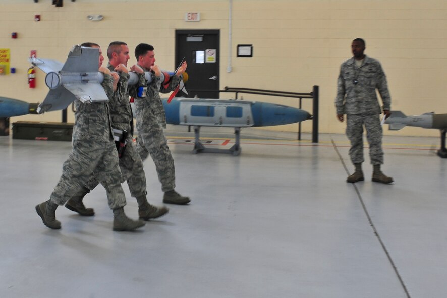 U.S. Air Force Senior Airman Ryan Castle, Staff Sgt. George Lesko and Airman 1st Class Levi Adams, 23d Aircraft Maintenance Squadron, 74th Aircraft Maintenance Unit weapons load crew members, carry a bomb to an A-10C Thunderbolt II during a weapons load crew of the quarter competition at Moody Air Force Base, Ga., April 13, 2012. The competition consisted of three-man teams from the 74th and 75th AMUs who competed to be the best load crew. (U.S. Air Force photo by Staff Sgt. Stephanie Mancha/Released)
