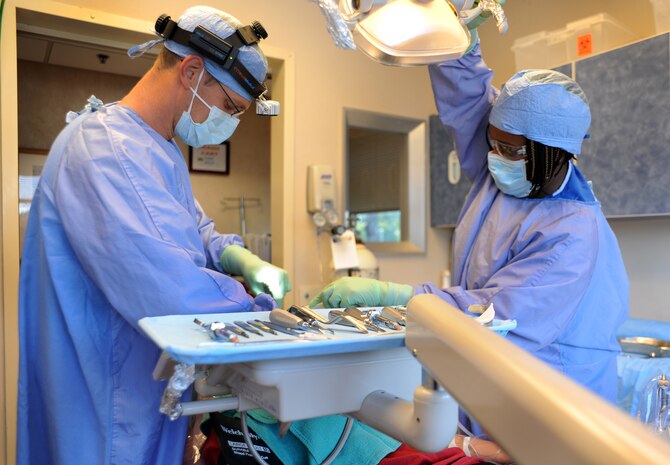 Capt. Aaron Cohenour and dental assistant Tanya Maisonet prepare for a wisdom tooth extraction at Joint Base Charleston - Air Base April 11. Cohenour and Maisonet are from the 628th Medical Group and Dyer is from the 628th Security Forces Squadron. (U.S. Air Force photo / Airman 1st Class Ashlee Galloway)