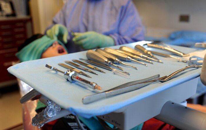Tools sit on a tray as Capt. Aaron Cohenour and dental assistant Tanya Maisonet prepare for a wisdom tooth extraction at Joint Base Charleston - Air Base April 11. Cohenour and Maisonet are from the 628th Medical Group and Dyer is from the 628th Security Forces Squadron. (U.S. Air Force photo / Airman 1st Class Ashlee Galloway)