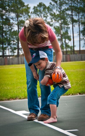 Hunter, three-years-old, hugs his mother, Tricia, wife of Staff Sgt. Justin Hoffman, 15th Airlift Squadron loadmaster, 437th Airlift Wing, while playing basketball together at an on-base park April 14. Hunter was diagnosed with moderate to severe classical autism recently. His autism limits his ability to speak, comprehend directions and understand certain social skills taught to children. Hunter may be limited in certain areas due to autism, but he excels with computers and retaining information. (U.S. Air Force photo by Airman 1st Class Dennis Sloan/Released)