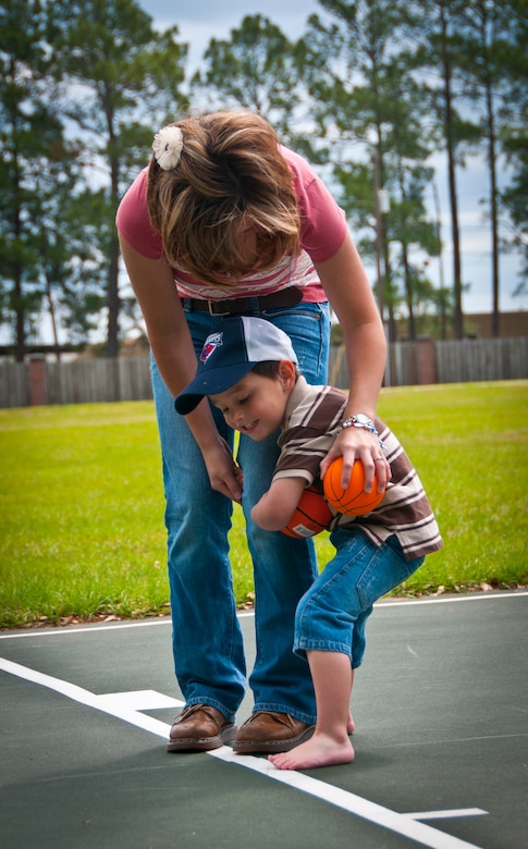 Hunter, three-years-old, hugs his mother, Tricia, wife of Staff Sgt. Justin Hoffman, 15th Airlift Squadron loadmaster, 437th Airlift Wing, while playing basketball together at an on-base park April 14. Hunter was diagnosed with moderate to severe classical autism recently. His autism limits his ability to speak, comprehend directions and understand certain social skills taught to children. Hunter may be limited in certain areas due to autism, but he excels with computers and retaining information. (U.S. Air Force photo by Airman 1st Class Dennis Sloan/Released)