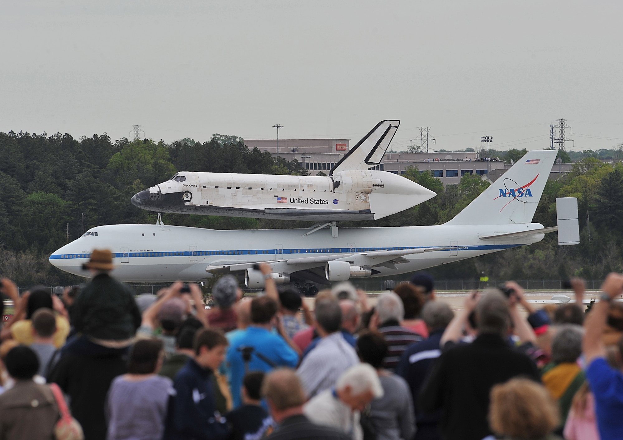 A crowd watches as the space shuttle Discovery, sitting on top of a modified NASA Boeing 747 aircraft, taxis on the runway at Washington Dulles International Airport in Dulles, Va., April 17, 2012. The Discovery made its final voyage to the Smithsonian National Air and Space Museum annex in Virginia. (U.S. Air Force photo by Val Gempis)