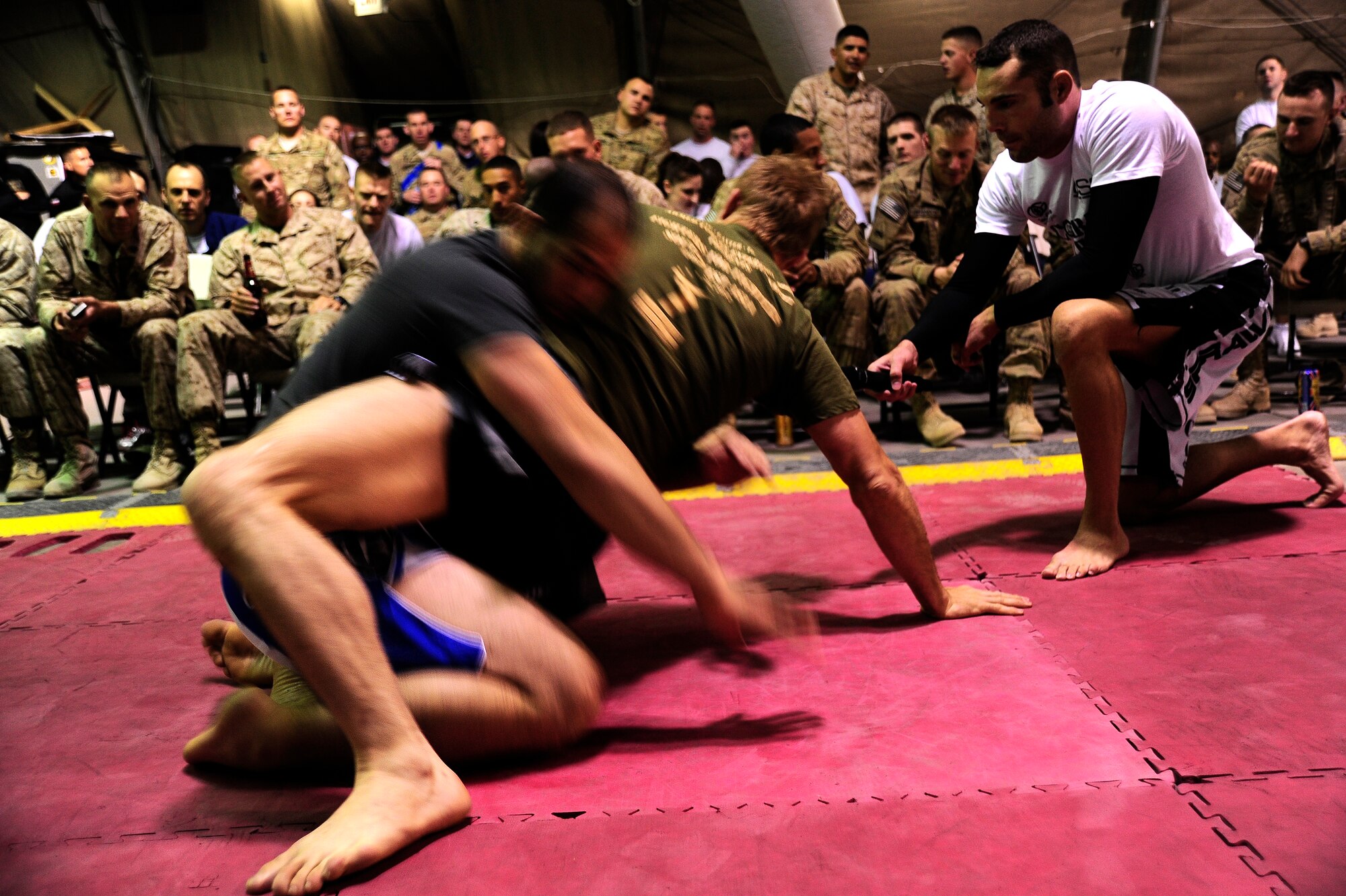 Mark Swick (far right) holds a microphone for Kurt Shrout (l) and Nick Ring (r), Ultimate Fighting Championship fighters,  while they give a mixed martial arts demonstration and explain what they are doing,  Pete's Place at the Transit Center at Manas, Kyrgyzstan, April 14, 2012. The UFC fighters are on a tour sponsored by Armed Forces Entertainment to raise morale among the troops. (U.S. Air Force photo/Senior Airman Lynsie Nichols)