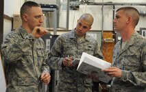 Pacific Air Forces Inspector General team member Tech. Sgt. Michael Wilson, right, and Airman 1st Class Travis Pratt, center, 8th Communications Squadron radio frequency transmissions systems technician, listen to Airman 1st Class Jordan Spangler, another systems technician, talk about removing corrosion from equipment. Wilson focused more on questioning newer technicians to ensure continued compliance. (U.S. Air Force photo/Senior Airman Brigitte N. Brantley)
