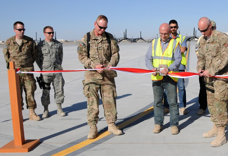 KANDAHAR AIR FIELD, Afghanistan — Air Force Col. Benjamin Wham, U.S. Army Corps of Engineers Afghanistan Engineer District South commander (left), Labib Bardawil, Contrack Inc. area manager (center), and Air Force Col. Sam Grable, 451st Air Expeditionary Mission Support Group commander, cut the ceremonial ribbon that marks the completion of the fourth phase of a Kandahar Airfield expansion in southern Afghanistan, April 10, 2012.