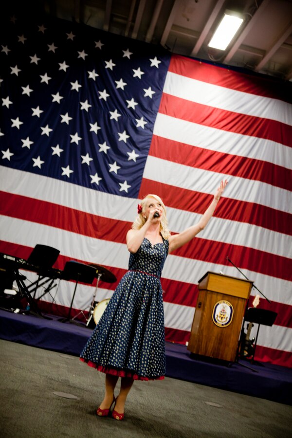 Cortney Boe of Victory Belles performs “God Bless America” during a Navy reception aboard USS Wasp held in honor of the War of 1812 Commemoration, April 18, 2012. New Orleans will serve as the inaugural city in a three-year national celebration commemorating the War of 1812 and the Star-Spangled Banner. The Marine Corps' role in this event reinforces its naval character, showcases the Navy-Marine Corps team and highlights the military's enduring relationship with the city of New Orleans. (U.S. Marine Corps photo by Lance Cpl. Marcin Platek/Released)