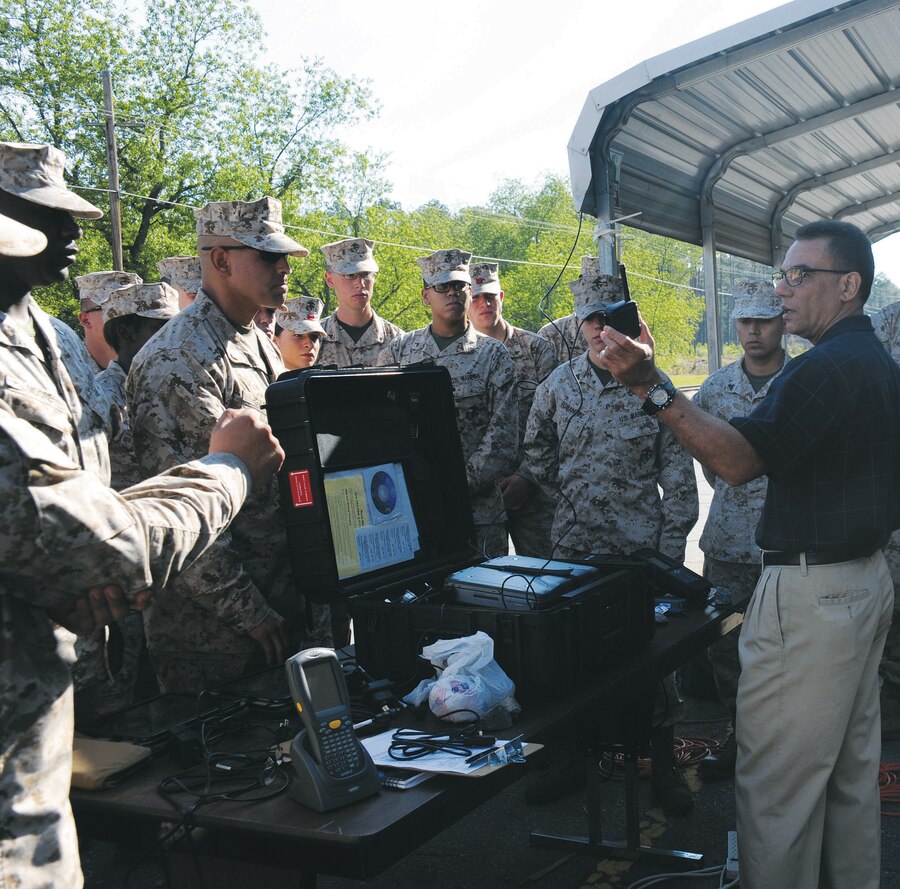 Rafael Batista, future operations chief, Distribution Management Center, teaches a group of Marines April 5 how to use a portable deployment kit, which is used to track Marine Corps’ equipment.