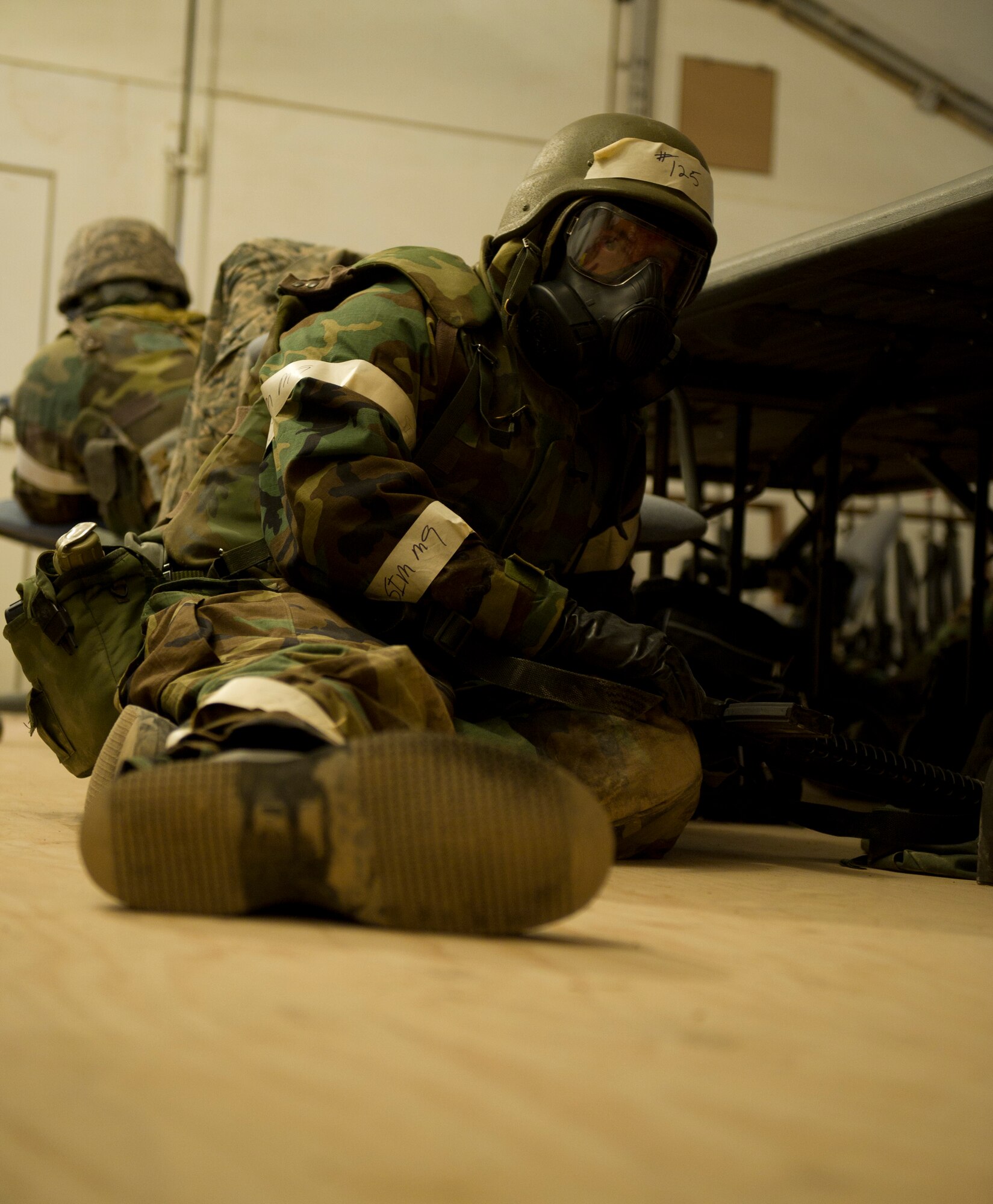HOLLOMAN AIR FORCE BASE, N.M. – Airmen from the 49th Civil Engineer and Materiel Maintenance Squadrons take cover under a hardened shelter in level four mission-oriented protective postures during a Bivouac exercise April 11. During a simulated base attack, Airmen sought immediate shelter in a solid-structure as a preventative measure, as well as donned chemical protection gear to protect themselves from any possible form of bio-warfare used by hostile forces. (U.S. Photo by Airman 1st Class Michael Shoemaker/Released)
