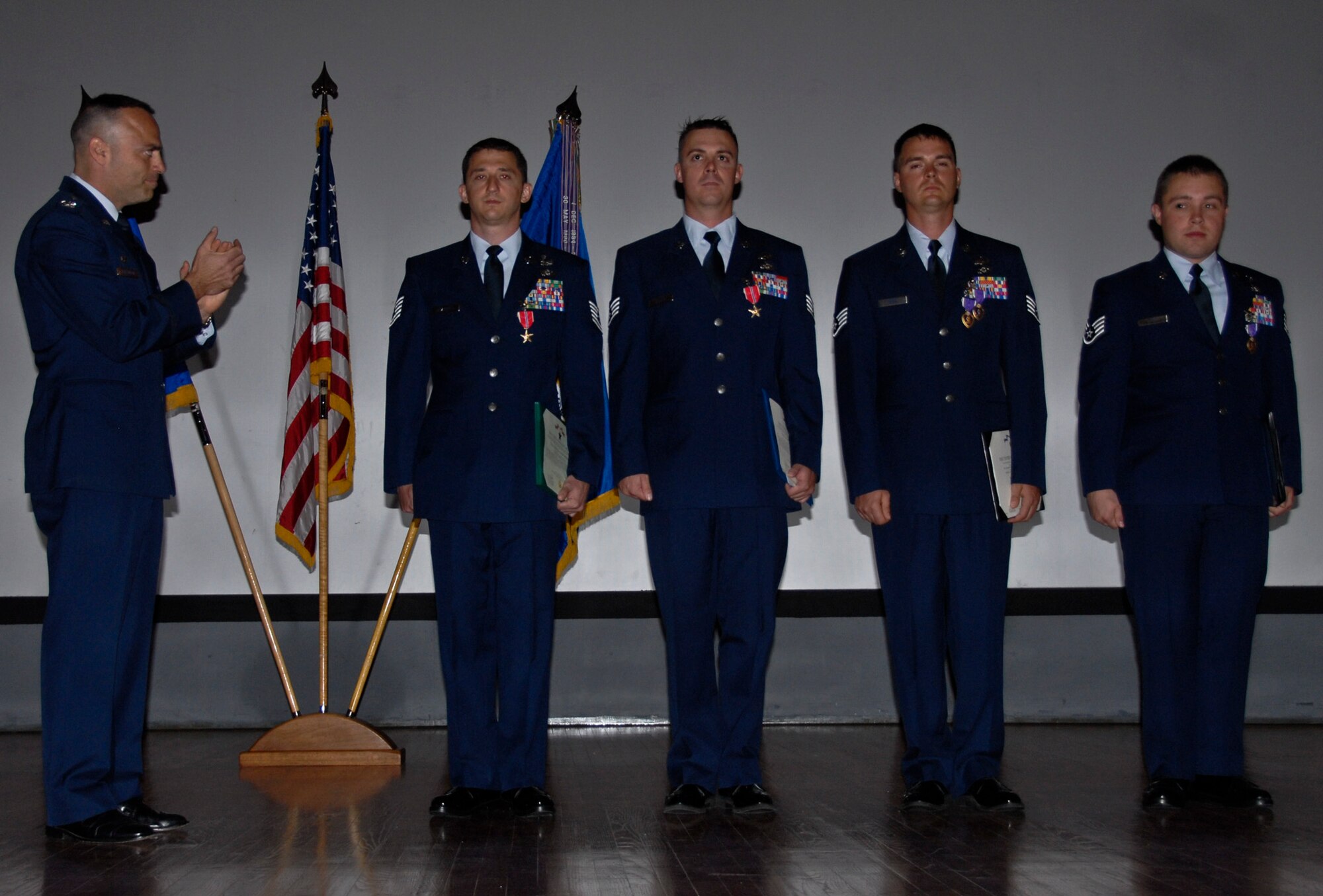 Col. Sal Nodjomian, 96th Air Base Wing commander, applauds the heroism of four Eglin Explosive Ordinance Disposal Airmen after pinning on Bronze Stars and Purple Hearts April 19.  Tech Sgt. James Fitzgerald and Staff Sgt. Kelly Badger were awarded Bronze Stars while Staff Sgts. Kevin Parke and Christopher Lacy were awarded the Purple Heart during the 96th Air Base Wing commanders call here. Parke was injured in two separate incidents in Afghanistan earning a second oak leaf cluster. (U.S. Air Force photo by Chrissy Cuttita)