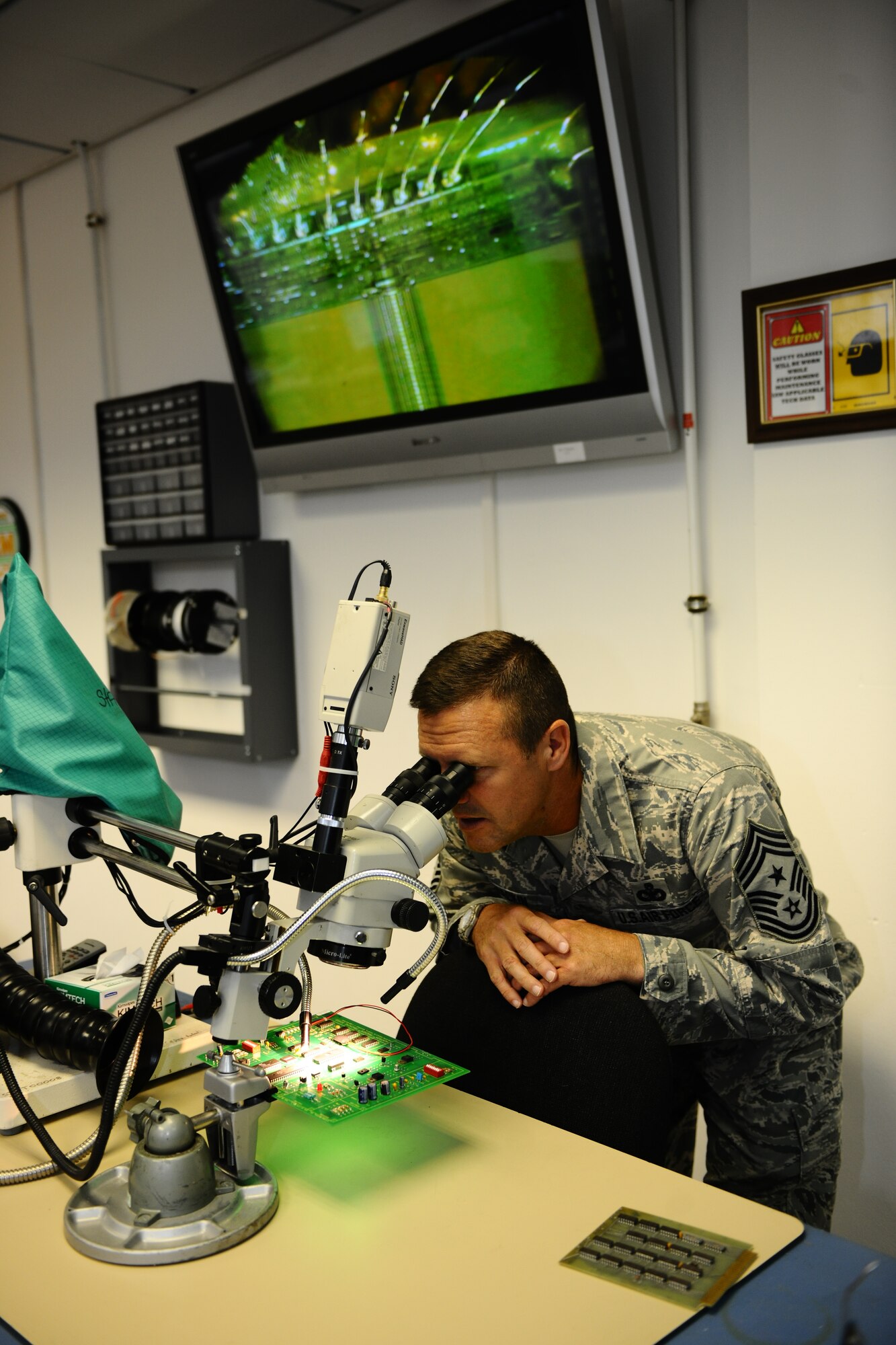 SPANGDAHLEM AIR BASE, Germany – Chief Master Sgt. Oscar Mackin, 2nd Air Force command chief, looks at a microchip through a microscope during a tour of 372nd Training Squadron Detachment 2 classrooms and training facilities inside Bldg. 43 here April 18. Maj. Gen. Leonard Patrick, 2nd AF commander, and Mackin visited the 372nd TRS Det 2 during their 2nd AF overseas units tour. The detachment offers advanced skills using classroom and hands-on training on the F-16 Fighting Falcon and A-10 Thunderbolt II for more than eight different aircraft maintenance career fields. (U.S. Air Force photo by Airman 1st Class Dillon Davis/Released)