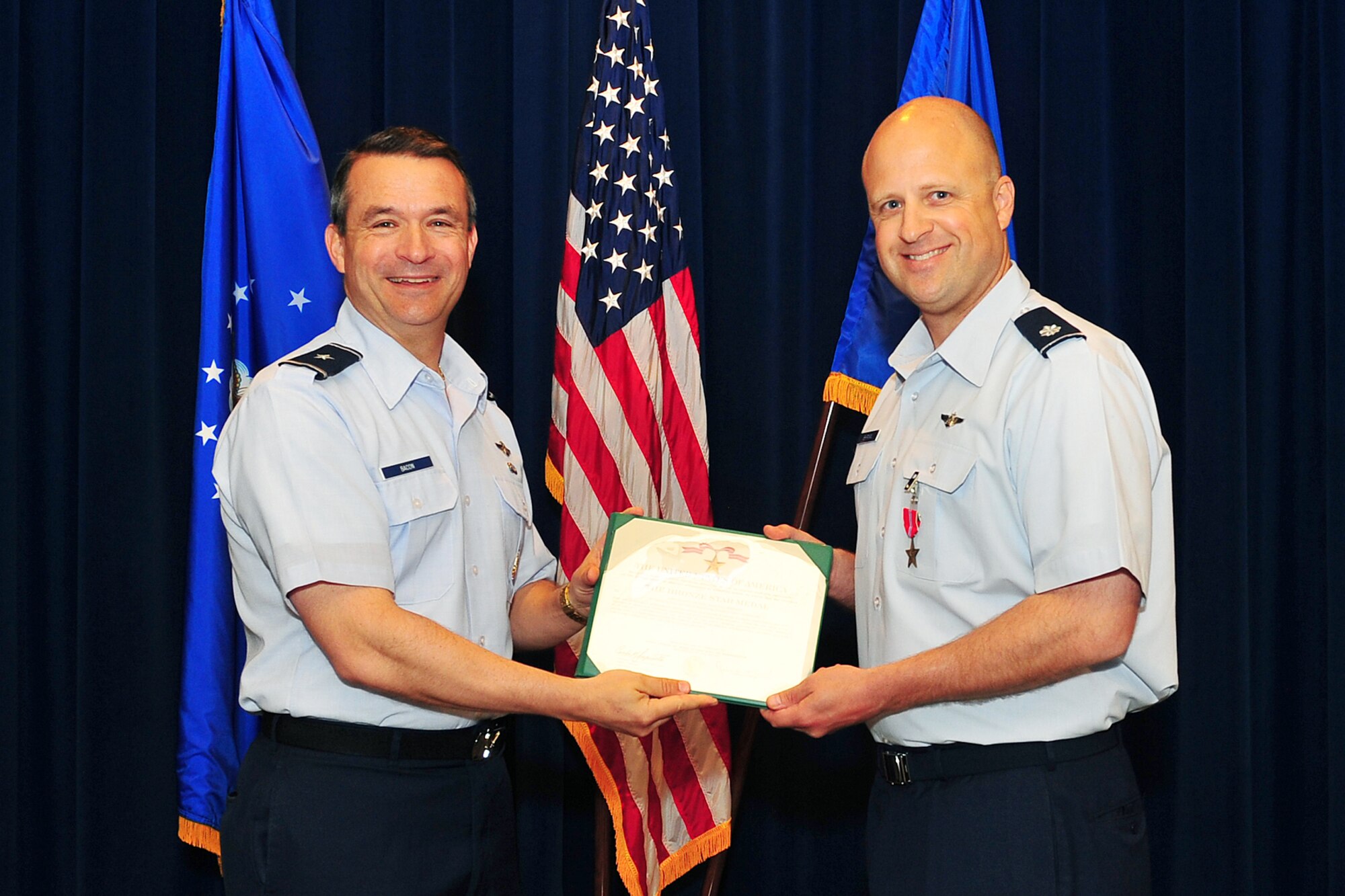 U.S. Air Force Brig. Gen. Donald Bacon, 55th Wing commander, presents U.S. Air Force Lt. Col. Marcus Shipman with a Bronze Star during the 55th Wing Staff meeting in the Dougherty Conference Center on Offutt Air Force Base, Neb., April 16.  Shipman provided direct electronic fire support and close air support apportionment to 14 provinces, 143 bases and seven brigade combat teams totaling more than 32,000 coalition forces. 
 
(U.S. Air Force photo by Charles Haymond/Released).  
