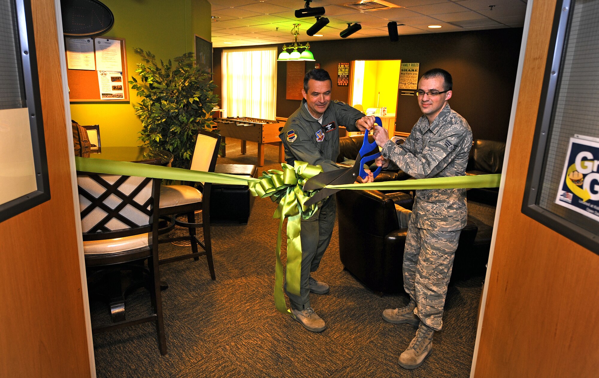 U.S. Air Force Brig. Gen. Donald Bacon, 55th Wing commander, performs the ceremonial ribbon cutting alongside Senior Airman Kyle Slack, 55th Intelligence Support Squadron, to commemorate the grand re-opening of The Connection, a dormitory morale room, which was recently relocated to the third floor of Tuskegee Hall at Offutt Air Force Base, Neb., April 17.  The Connection provides Airmen with a computer workstation, full kitchen, gaming room, high definition television and a coffee station. (U.S. Air Force photo by Josh Plueger/Released).