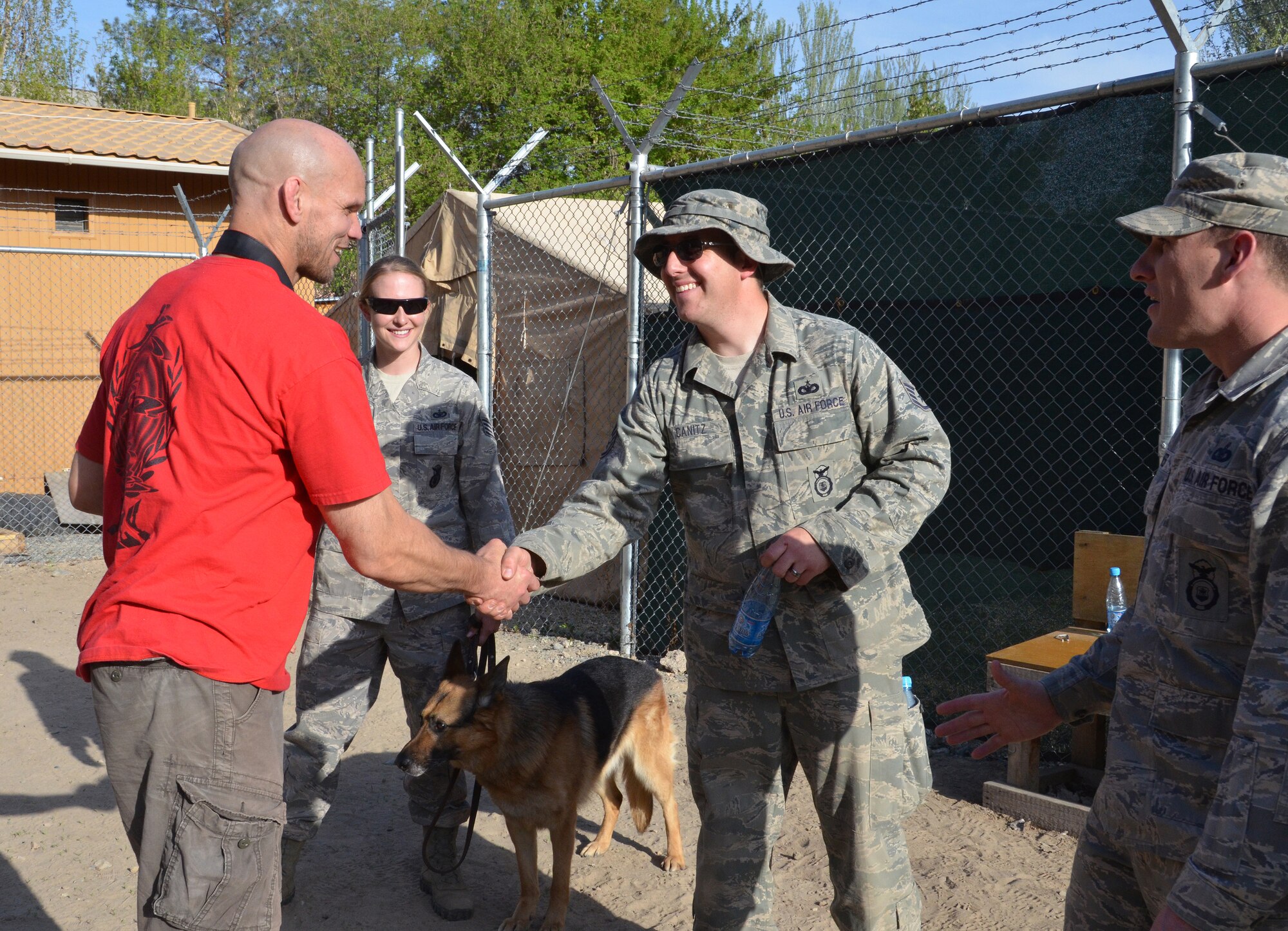 Gregory Scott, an Ultimate Fighting Championship fighter, shakes hands with Staff Sgt. Daniel Canitz, 376th Expeditionary Security Forces Squadron military working dog handler stationed at the Transit Center at Manas, Kyrgyzstan, April 14, 2012. Canitz, along with other 376 ESFS dog handlers, hosted a military working dog demonstration allowing the UFC fighters to don the bite suit and experience bite and hold sequences with the dogs. These sequences are designed to detain suspects long enough for law enforcement officials to make contact with the suspect. The UFC fighters visited the Transit Center as part of an Armed Forces Entertainment tour.   (U.S. Air Force photo/Courtesy Photo)