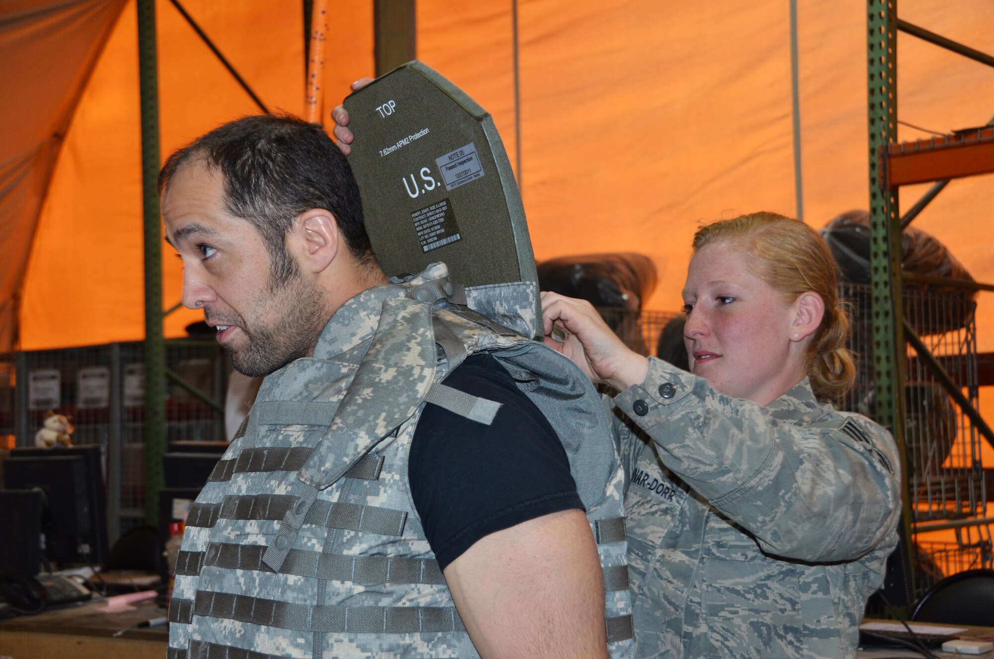 Senior Airman Margaret Kushnar-Dorr, 367th Expeditionary Logistics Readiness Squadron expeditionary theater distribution center technician, slides an ESAPI front/back plate into an improved body armor vest for Ultimate Fighting Championship fighter Kurt Shrout April 14, 2012, Transit Center at Manas, Kyrgyzstan. Shrout, along with four other UFC fighters, were visiting the Transit Center before heading to Afghanistan as part of an Armed Forces Entertainment tour.  Kushnar-Dorr is deployed here from Dyess Air Force Base, Texas, and her hometown is Cleveland, Ohio. (U.S. Air Force photo/Courtesy Photo)