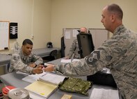 Senior Master Sgt. Michael Hudson, Pacific Air Force Inspector General team member, hands a piece of aircrew chemical defense gear to Tech. Sgt. Rikki Carpenter, 8th Operations Support Squadron aircrew flight equipment specialist, on Kunsan Air Base, Republic of Korea, April 19, 2012. Each piece of the Aircrew chemical defense ensemble was inspected for proper function. (U.S. Air Force photo/Senior Airman Jessica Hines) 