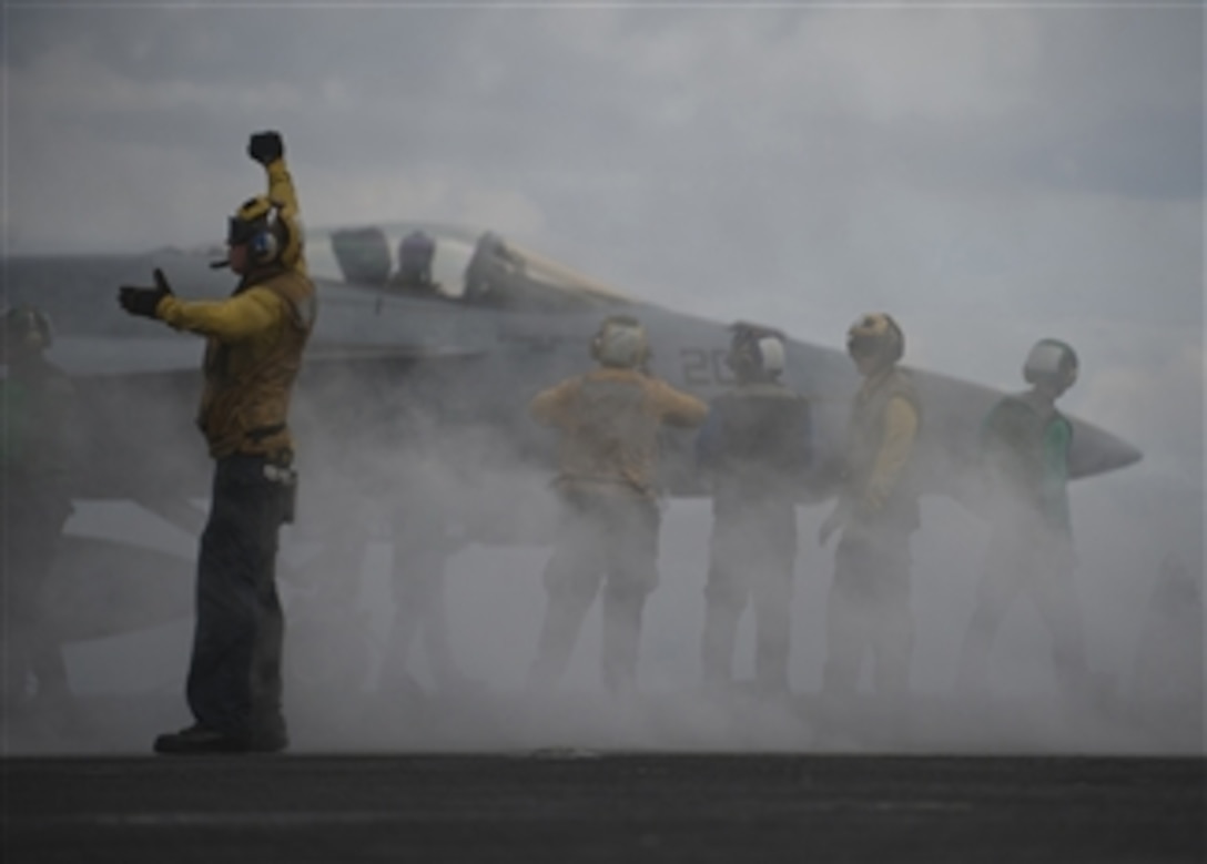 An aircraft director guides an F/A-18 Hornet onto the bow catapults for launch on the flight deck of the aircraft carrier USS Carl Vinson (CVN 70) Underway in Indian Ocean on April 16, 2012.  The Carl Vinson and Carrier Air Wing 17 are deployed participating in Exercise Malabar 2012 with ships and aircraft from the Indian Navy.  