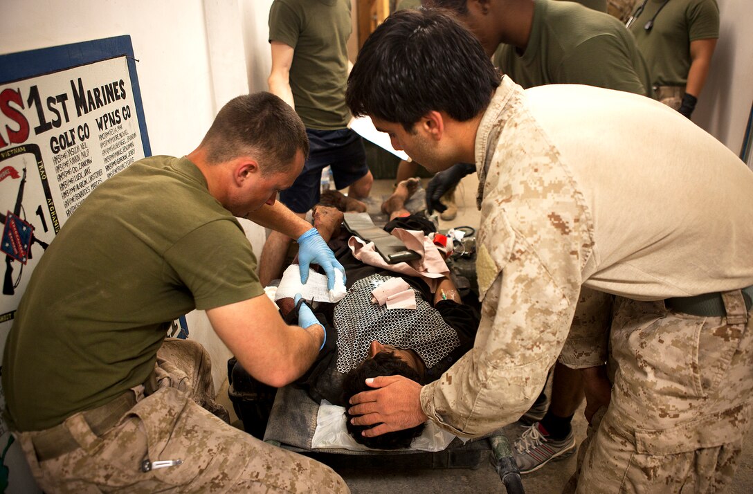 U.S. Navy Petty Officer 3rd Class Christopher Jones (left), a corpsman with 4th Platoon, Kilo Company, 3rd Battalion, 3rd Marine Regiment, and a 22-year-old native of Clinton, Miss., bandages an Afghan National Policeman’s arm outside the battalion aid station here after he was injured in an attack by a suicide bomber in Helmand province’s Garmsir district, April 19, 2012. The 3/3 corpsmen treated eight injured Afghan policemen after being faced with a mass casualty situation following the attack on an ANP precinct headquarters in Garmsir’s Lakari region. Ten of the 18 total ANP casualties died from wounds sustained in the attack. After initially being stabilized by three 3/3 corpsmen at Combat Outpost Sharp, eight casualties were transported to FOB Delhi and treated by a team of 28 Navy personnel. Medical evacuation helicopters later transported six ANP casualties to Camp Dwyer’s Casualty Support Hospital for further treatment, while the remaining two were treated and released.
