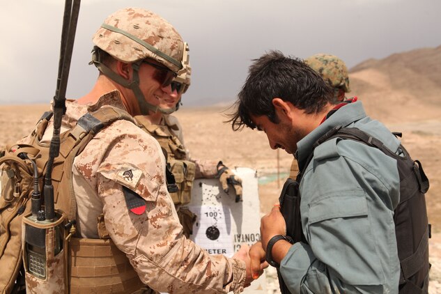 Sergeant Joshua Vance Armstrong, team leader serving with 1st Battalion, 8th Marine Regiment, Police Advisory Team 1, congratulates an Afghan Uniformed Police officer during a rifle marksmanship range here April 19, 2012. The officer was originally aiming too high, but after taking advice from Armstrong, he hit the center of the target ten times in a row. Armstrong, a native of Timber Lake, N.C., and rest of the PAT work closely with the AUP to prepare them to take full responsibility for security operations here. (U.S. Marine Corps photo by Lance Cpl. Tyler Reiriz)