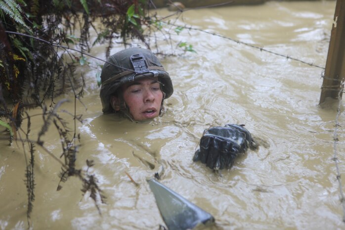 A Marine with 2nd Platoon, Company B., Battalion Landing Team 1st Battalion, 4th Marines, 31st Marine Expeditionary Unit, crawls through a watery ditch and under concertina wire during the Jungle Endurance Course here, April 20. After completing a two-week training evolution at the Jungle Warfare Training Center, the Marines underwent the four-mile-long course through the Okinawan jungle, utilizing the rappelling, rope-crossing, improvised stretcher carry and other skills they learned. The 31st MEU is the only continuously forward-deployed MEU and remains the nation’s force in readiness in the Asia-Pacific region.