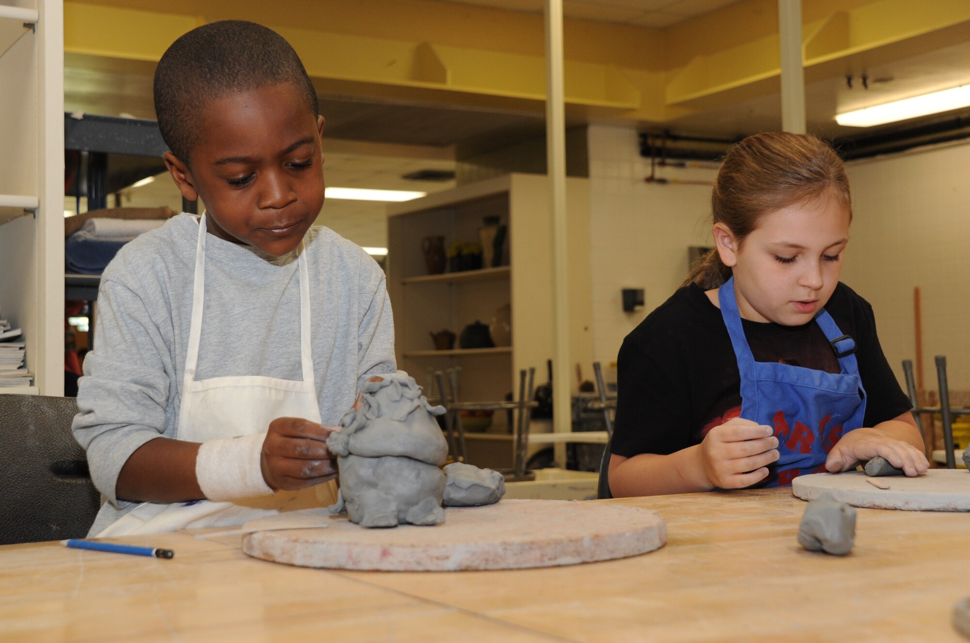 Amar Holiday (left), 6, son of Monica Holiday, Naval Air Systems Command Lakehurst, and Alia Dolka, 8, granddaughter of retired service members, work on their pottery skills during a children’s pottery class April 14 at the Arts and Crafts Center here. Holiday is putting the finishing touches on his snapping turtle while Dolka rolls the clay to add to her teapot. (U.S. Air Force photo by Senior Airman Bryan Swink/Released)