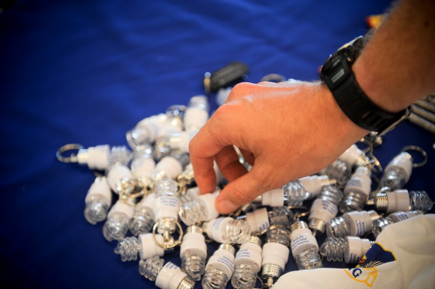 A CFL light bulb-keychain is picked up from an Earth Day booth at Moody Air Force Base, Ga., April 19, 2012. The Earth Day booth was set up to inform Moody members on the importance of recycling and conserving energy. (U.S. Air Force photo by Airman 1st Class Douglas Ellis/Released)
