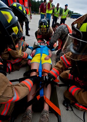 Sarah Massengill, a victim of a simulated aircraft fire is secured before emergency responders move her to the triage area during a mass casualty exercise at the Northwest Florida Regional Airport April 19.  The scenario called for emergency units from Eglin, Okaloosa County and the airport to respond to an aircraft on fire containing more than 40 passengers.  Response, communication and accountability were among many procedures under evaluation at the exercise.  Inside the airport, employees were tested on their response to an influx of friends and family members looking for information about the accident.  The Federal Aviation Administration mandates this type of major accident exercise execution every three years.  (U.S. Air Force photo/Samuel King Jr.)