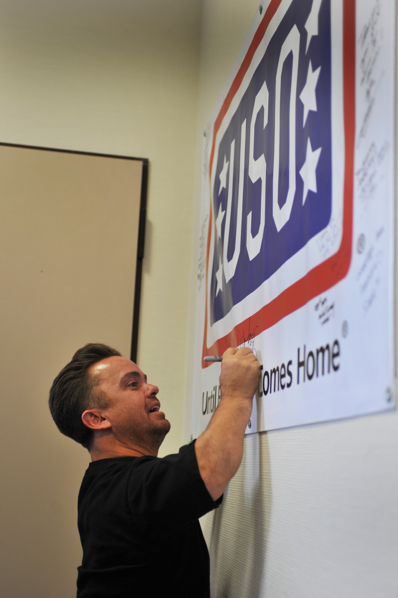 Actor Jason “Wee Man” Acuna signs a United Services Organization banner at the Contingency Aeromedical Staging Facility on Ramstein Air Base, Germany, April 20, 2012. During the United Services Organization and Armed Forces Entertainment tour, the ninth Vice Chairman of the Joint Chiefs of Staff, joined with a cast of entertainers, visited with troops stationed overseas. The tour consisted of live performances, and the group visited different organizations throughout the Kaiserslautern Military Community. (U.S. Air Force photo/Airman 1st Class Caitlin O'Neil-McKeown)