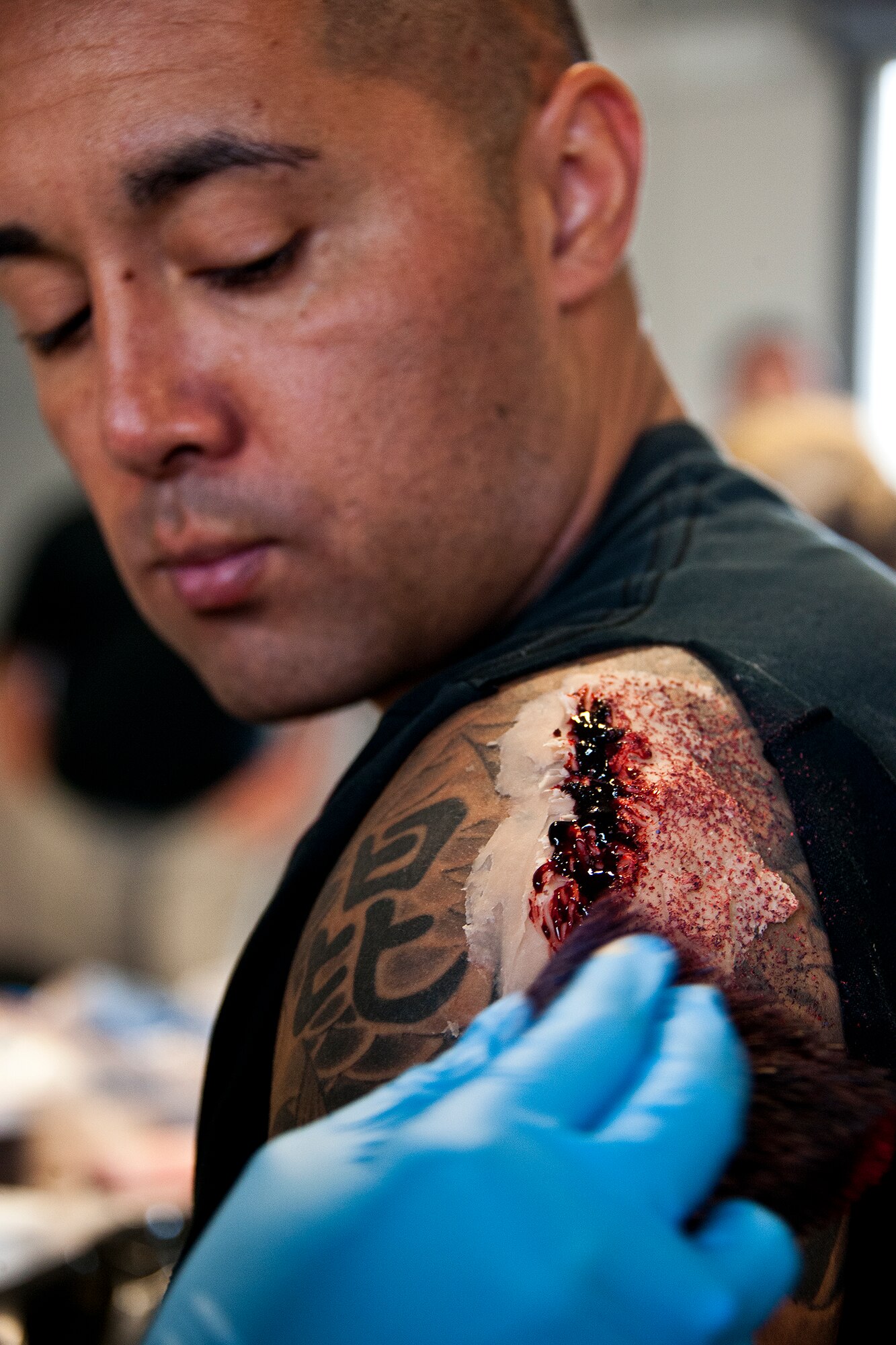 Staff Sgt. Edward Borges, of the 96th Logistics Readiness Squadron, has a large bloody gash placed onto his arm prior to a mass casualty exercise April 19. The 96th Medical Group moulage team turned more than 40 volunteers into ‘horror movie’ realistic victims of an aircraft fire.  The team’s “art” provides a sense of realism in exercises that medics and first responders may encounter in real-world accidents.  (U.S. Air Force photo/Samuel King Jr.)