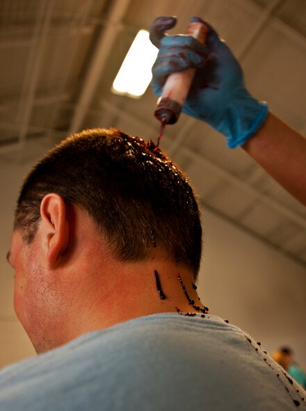 A 96th Medical Group moulage team member creates blood spatter on a volunteer prior to a mass casualty exercise April 19. The moulage team turned more than 40 volunteers into ‘horror movie’ realistic victims of an aircraft fire.  The team’s “art” provides a sense of realism in exercises that medics and first responders may encounter in real-world accidents.  (U.S. Air Force photo/Samuel King Jr.)