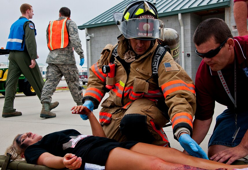 An Eglin firefighter and a Northwest Florida Regional Airport employee evaluate a victim of a simulated aircraft fire as medical personnel walk to the next victim during a mass casualty exercise at the Northwest Florida Regional Airport April 19.  The scenario called for emergency units from Eglin, Okaloosa County and the airport to respond to an aircraft on fire containing more than 40 passengers.  Response, communication and accountability were among many procedures under evaluation at the exercise.  Inside the airport, employees were tested on their response to an influx of friends and family members (of the simulated victims) looking for information about the accident.  The Federal Aviation Administration mandates this type of major accident exercise execution every three years.  (U.S. Air Force photo/Samuel King Jr.)